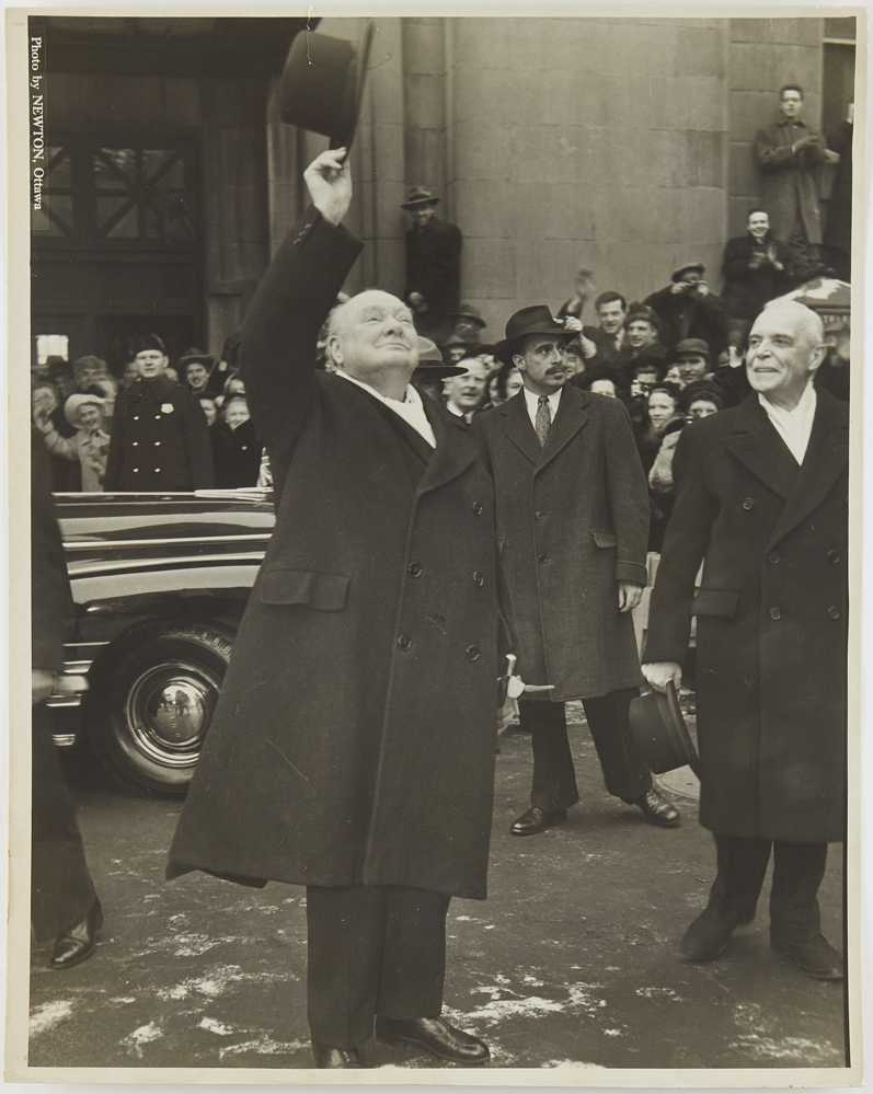 Photograph of Winston Churchill waving his hat at a crowd